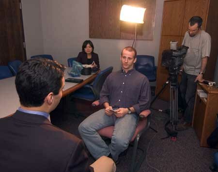 Jafar Karim, Deputy Secretary of the Department of Tourism and State Development, is interviewed by Bettag. Looking on are Hiroe Fujihara, correspondent, and Brian Dentz, camera person